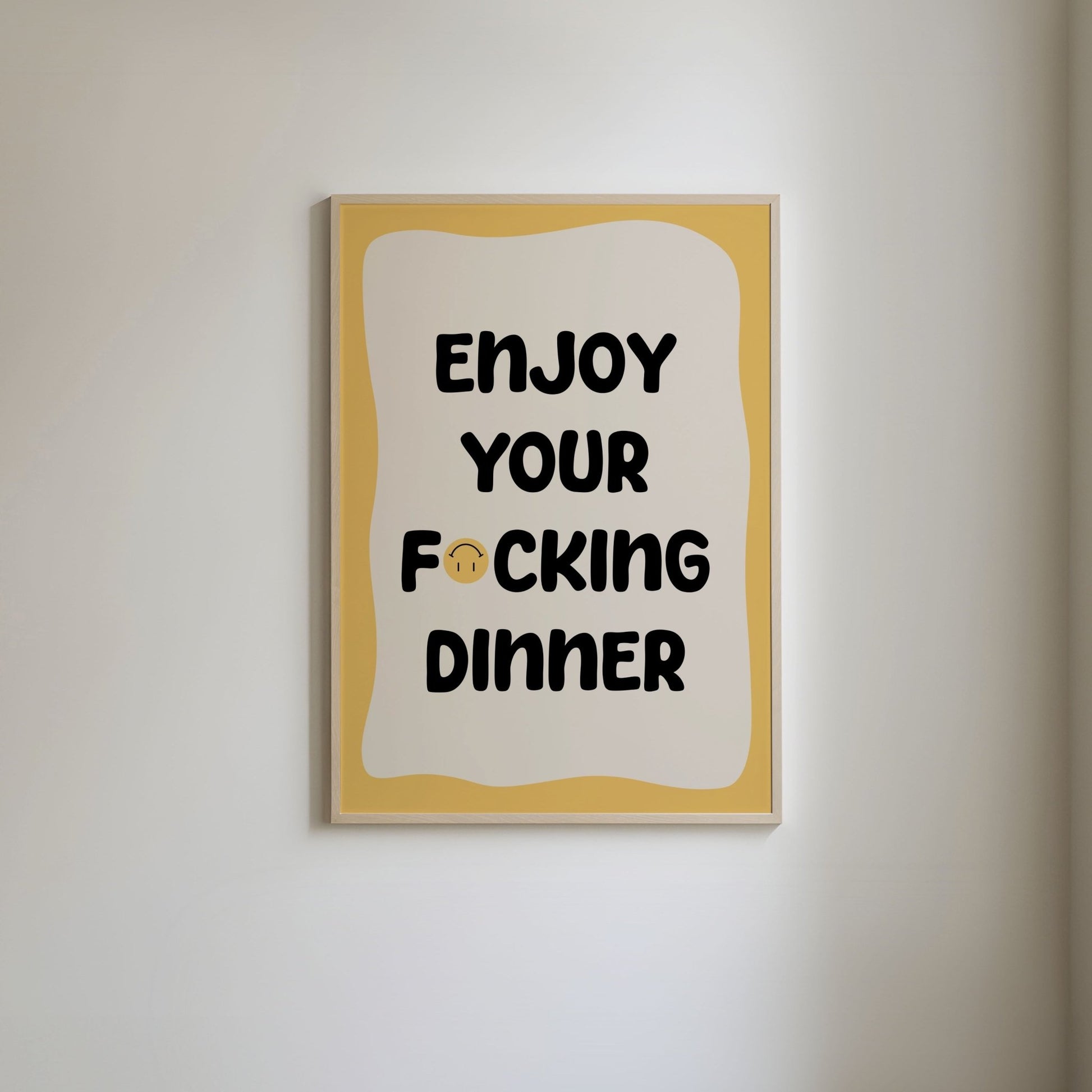 Art print with a yellow border and bold text 'Enjoy your fucking dinner,' with an upside down yellow smiley face covering part of the word 'fucking".