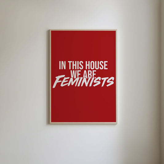 Art print with a red background and bold white text that reads 'In this house we are feminists.